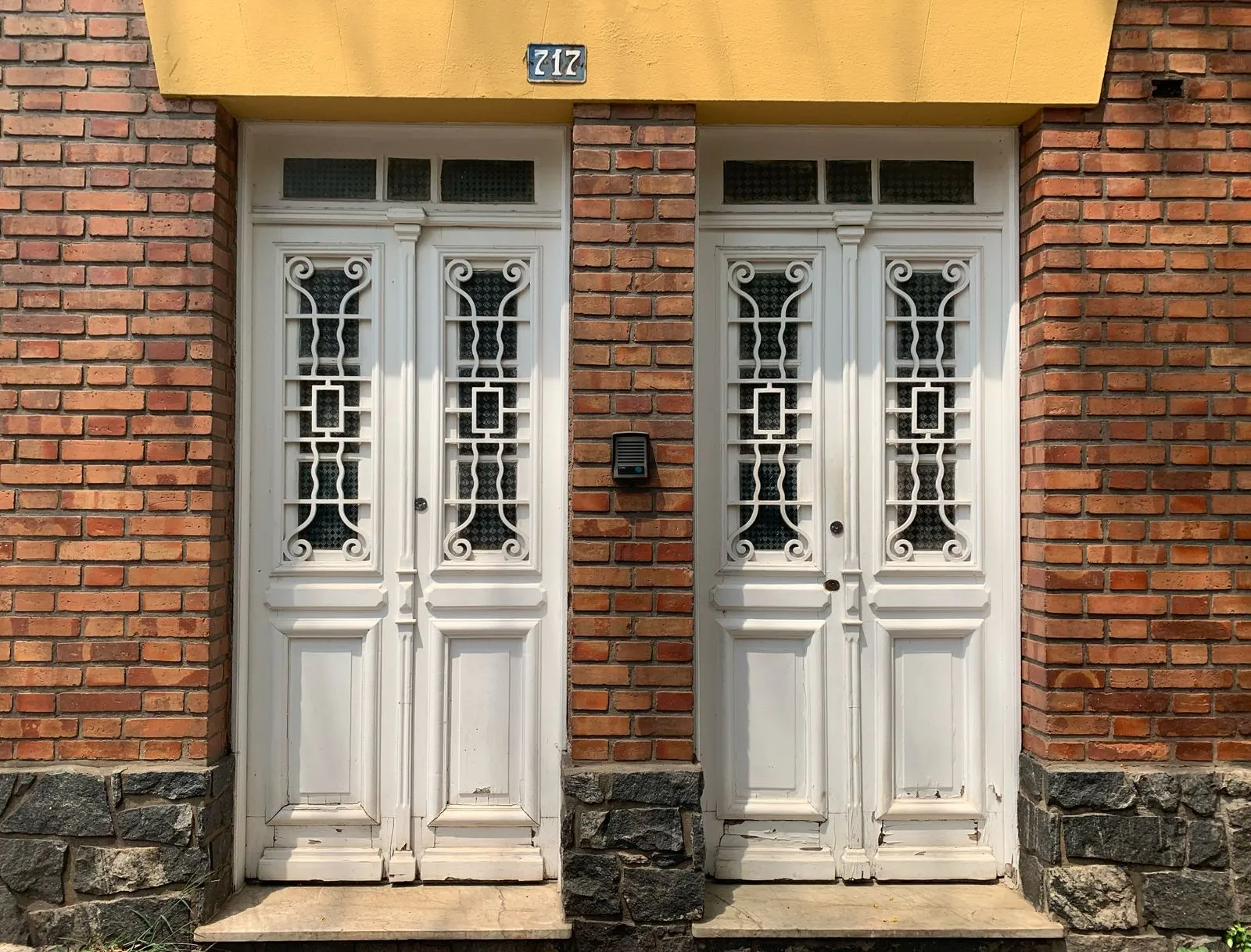 White ornate double doors set against a red brick facade with intercom and house number 217.